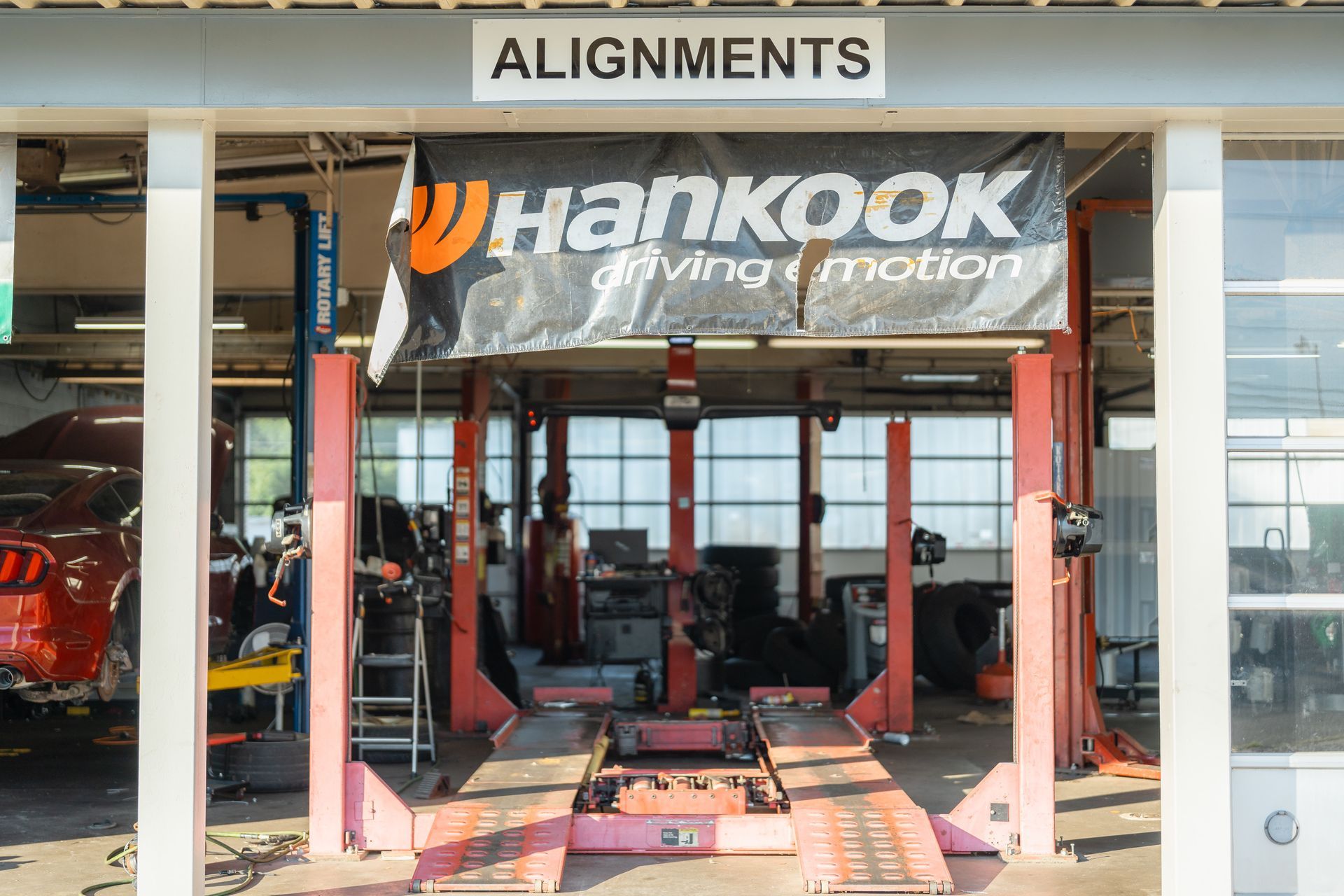 Auto alignment shop with a Hankook banner and vehicle lifts inside a garage.