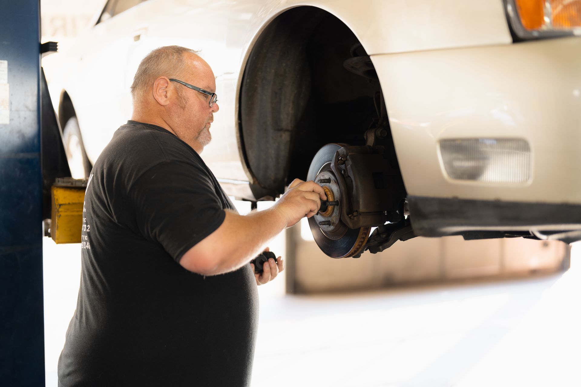 Mechanic inspecting a car’s front brake assembly in a garage