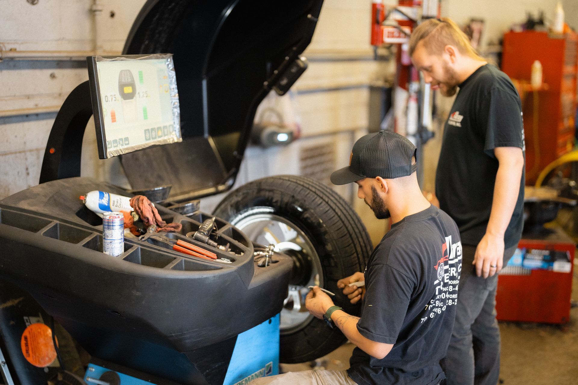 Two mechanics working on a car in a garage with the hood open
