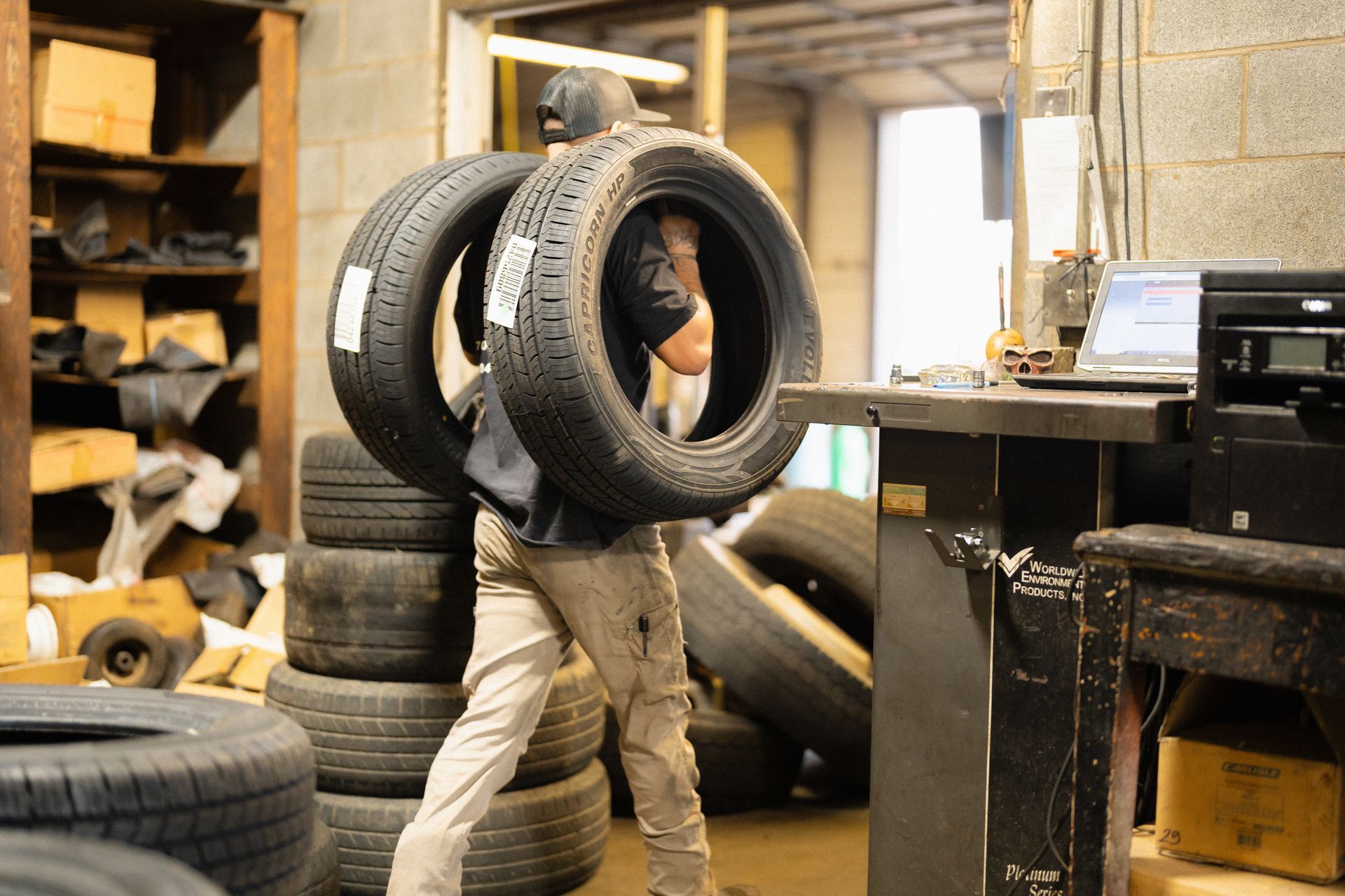 Person carrying stacked tires through a cluttered workshop