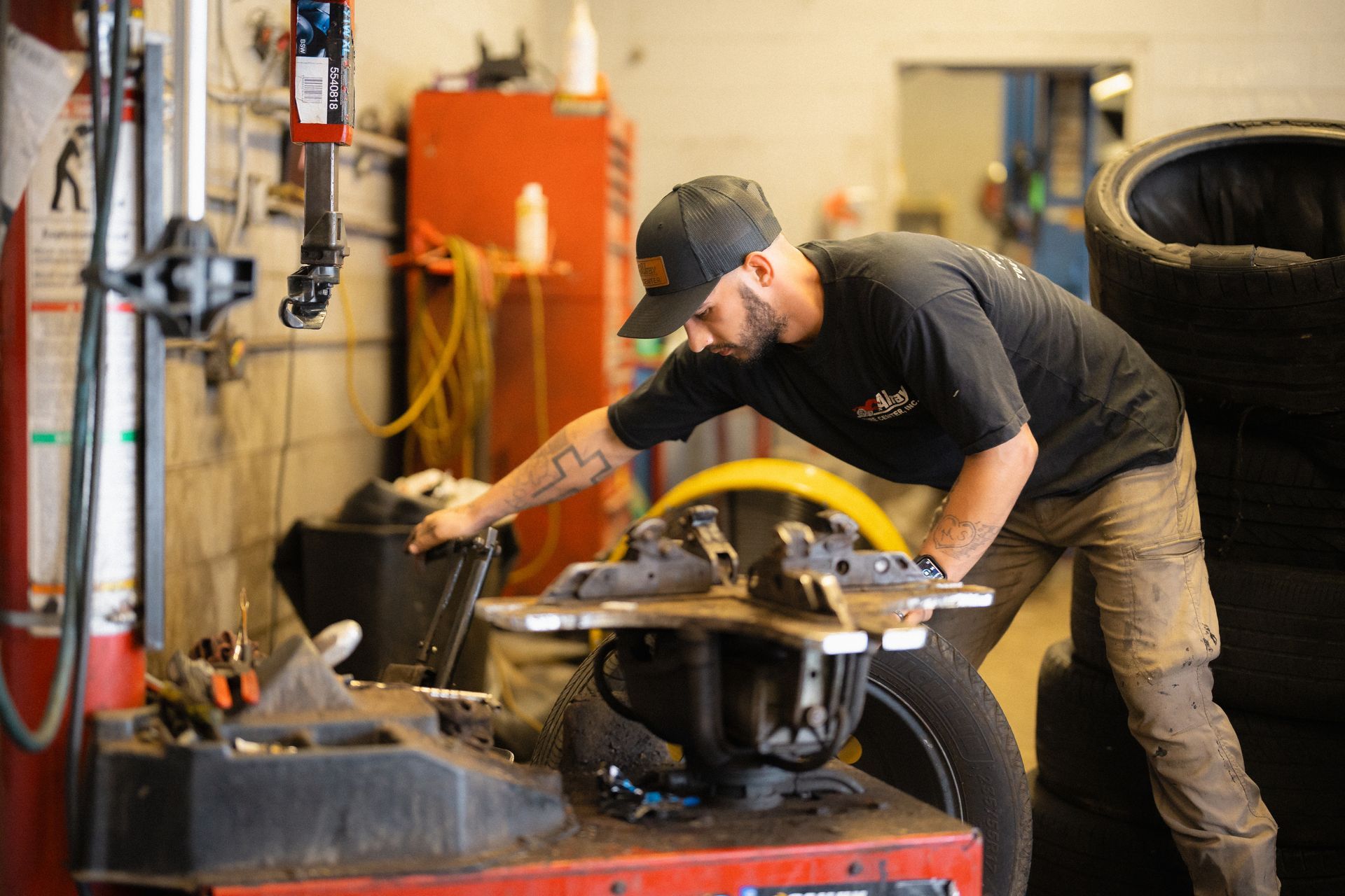 Mechanic welding a car frame in a cluttered auto shop, with tools and equipment nearby