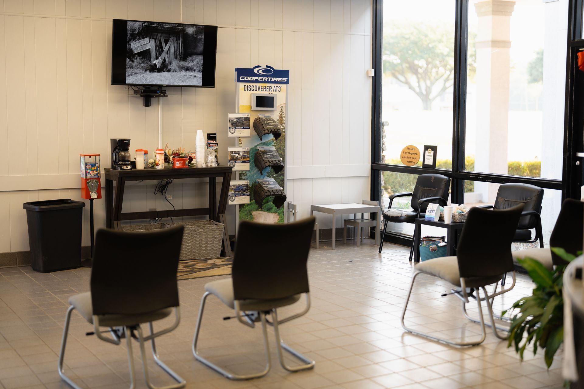 Waiting area with chairs, magazine rack, and TV in a bright lobby