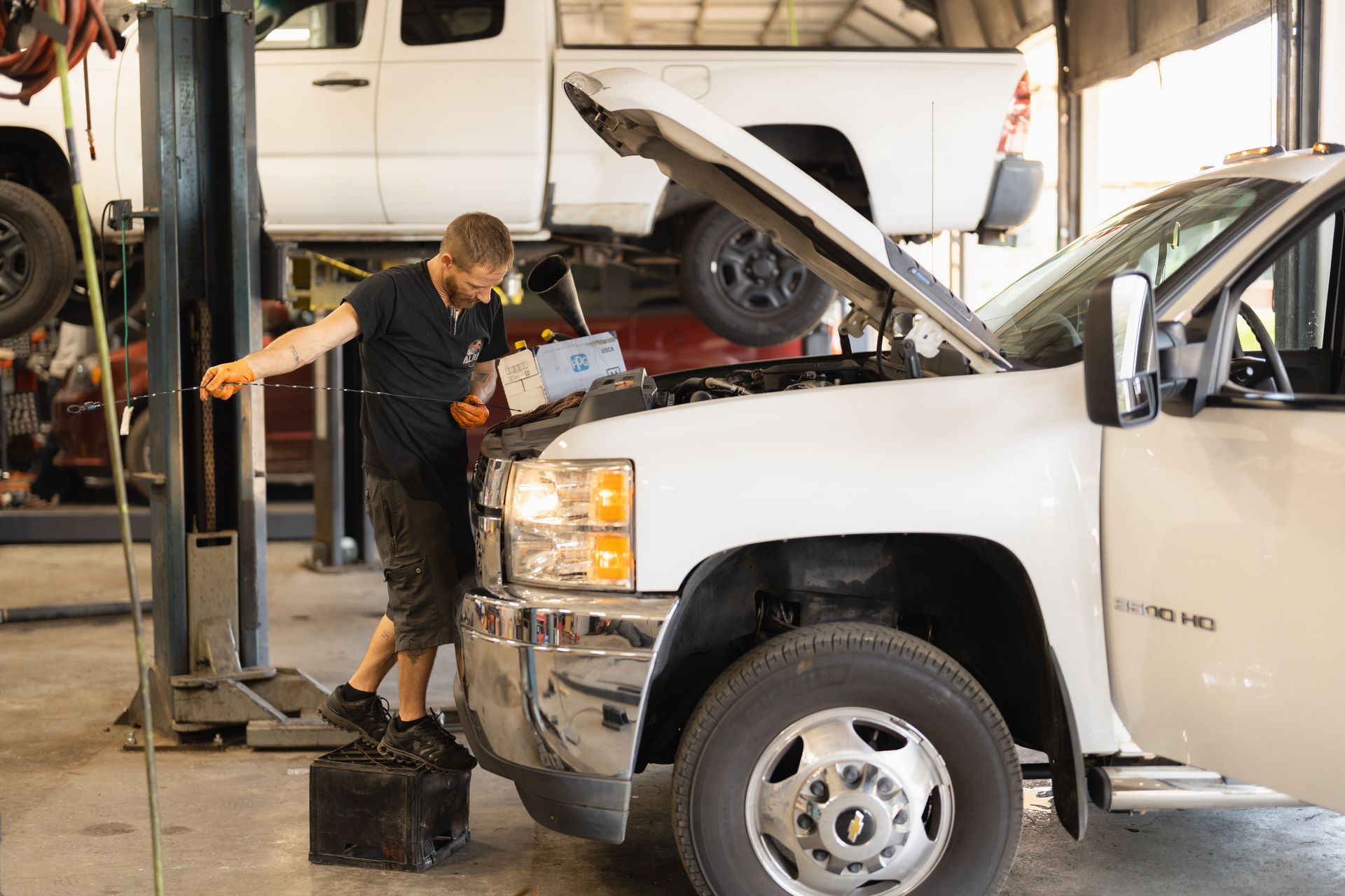 Mechanic working on a white truck with the hood open in an auto repair shop