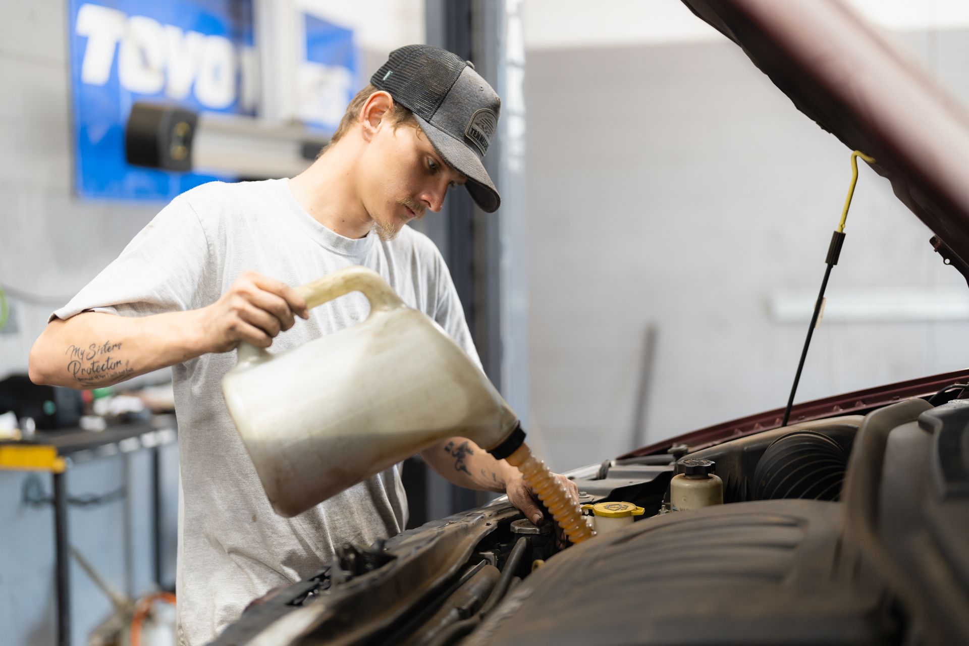 Mechanic pouring oil into a car engine in a garage