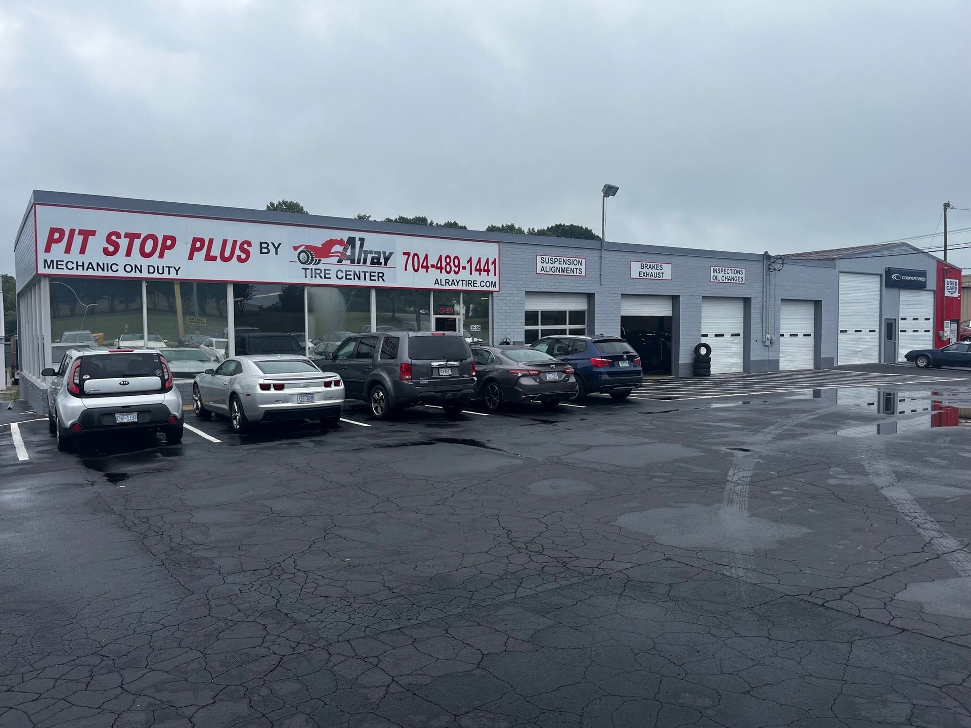 Pit Stop Plus auto repair shop with parked cars on a wet, snowy lot