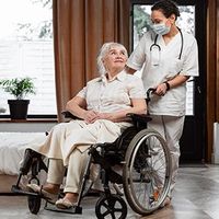 Nurse assisting elderly patient in wheelchair in a bright room