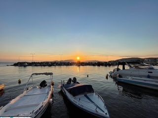 Sunset over calm harbor with three docked boats and a glowing orange horizon
