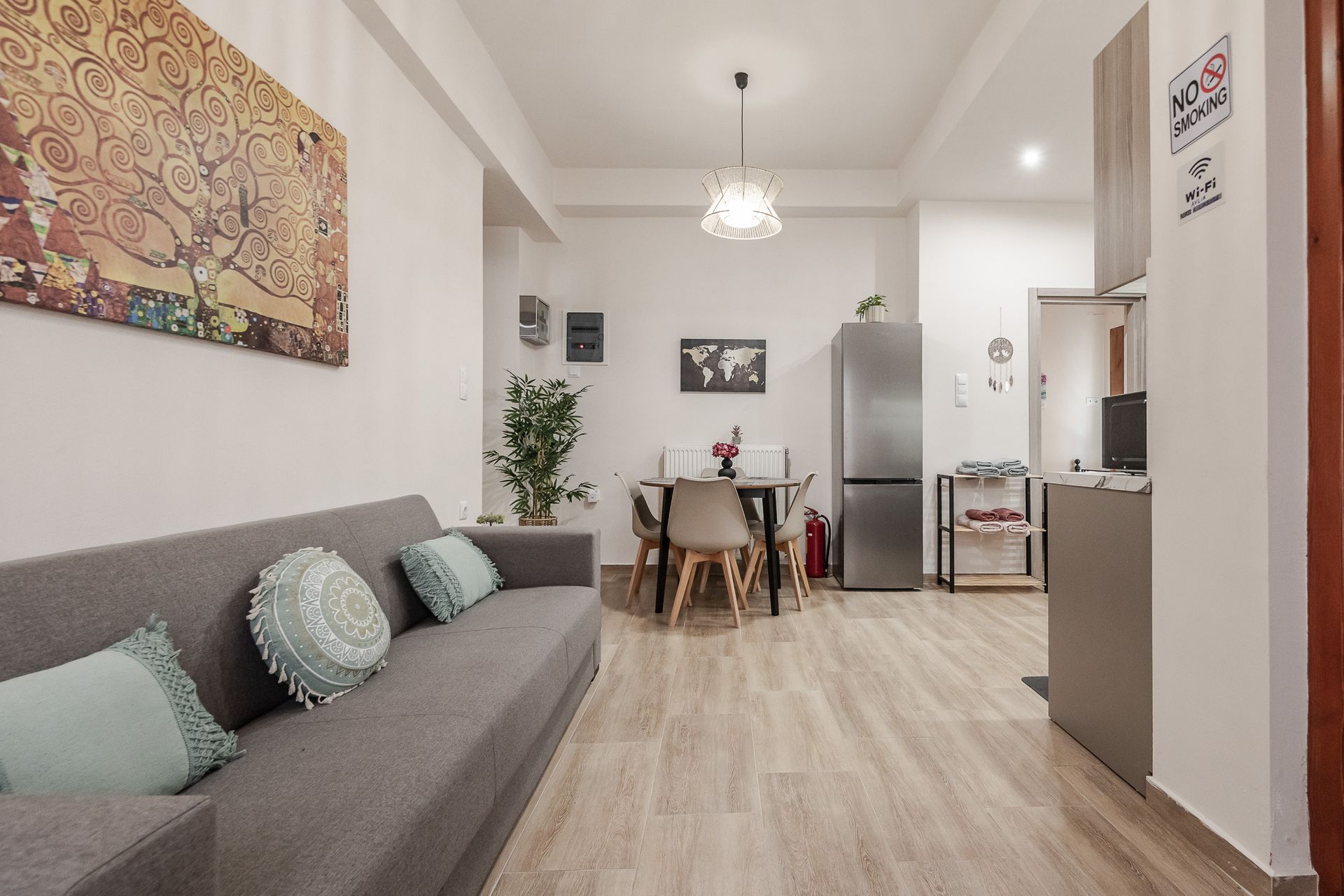 Bright living room with gray sofa, dining table, and open kitchen in a modern apartment