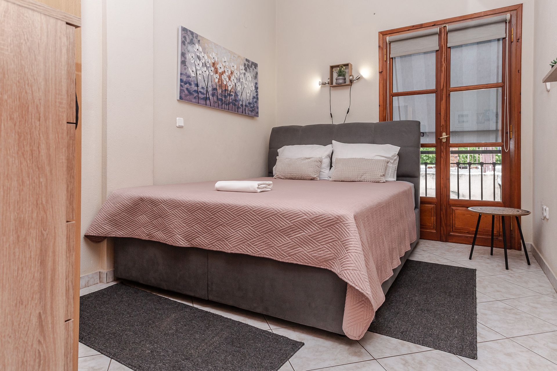 Small bedroom with a double bed, gray bedding, wall art, and a balcony door.