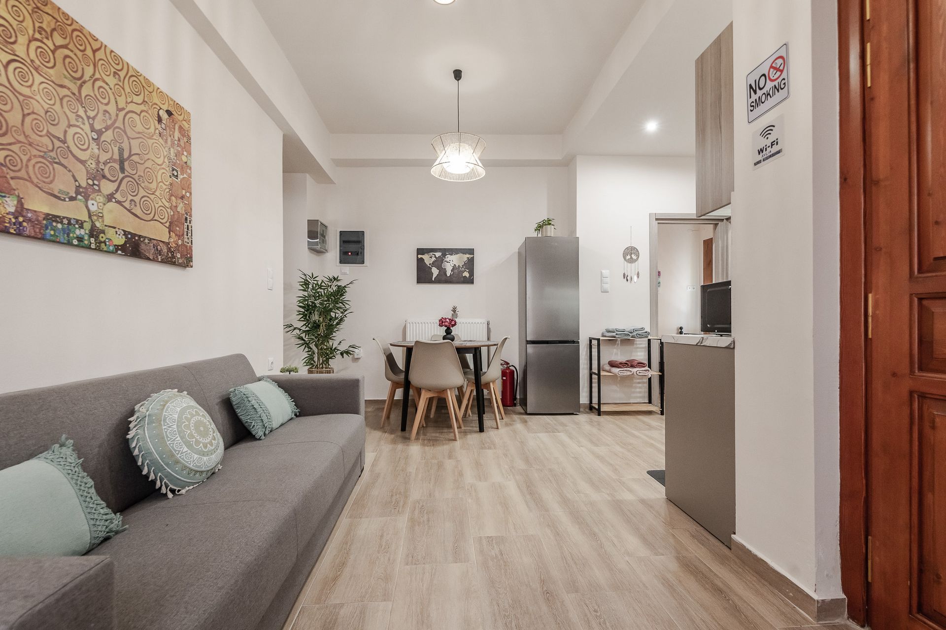 Modern living room with gray sofa, dining table, and open kitchen in a bright apartment