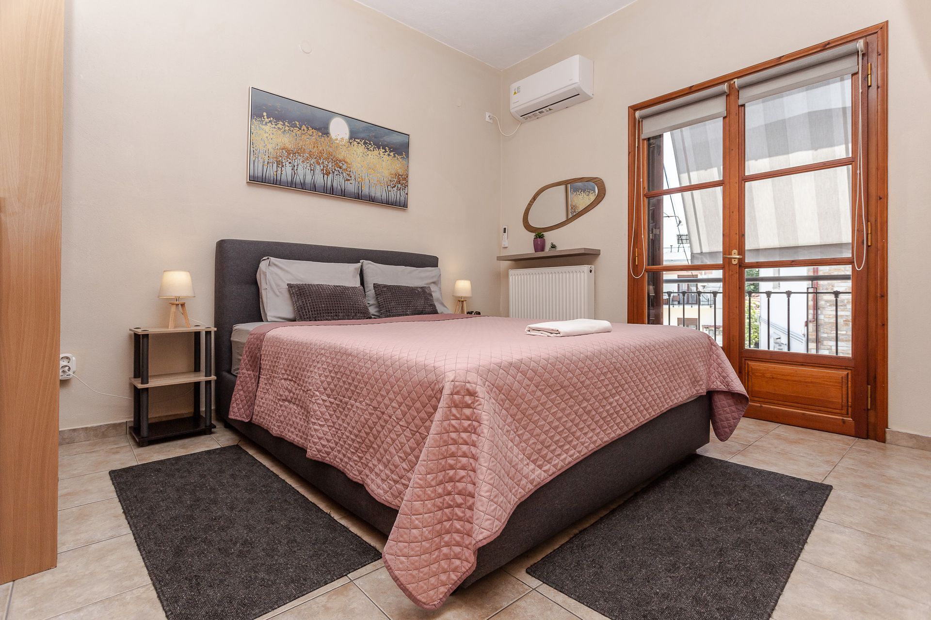 Bright bedroom with a bed, bedside tables, wall art, and a balcony door