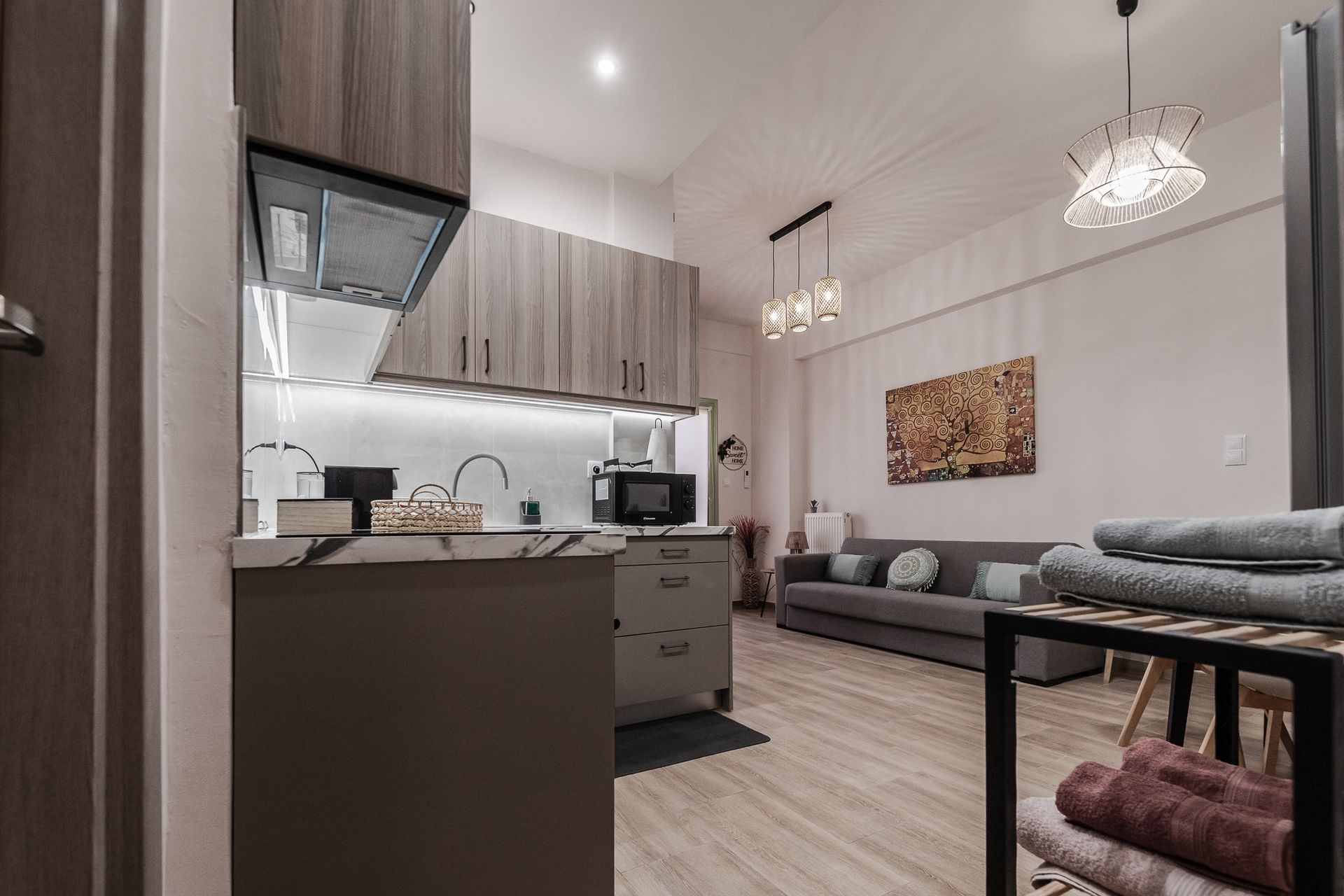 Open-plan studio with kitchen, sofa, dining table, and hanging pendant lights