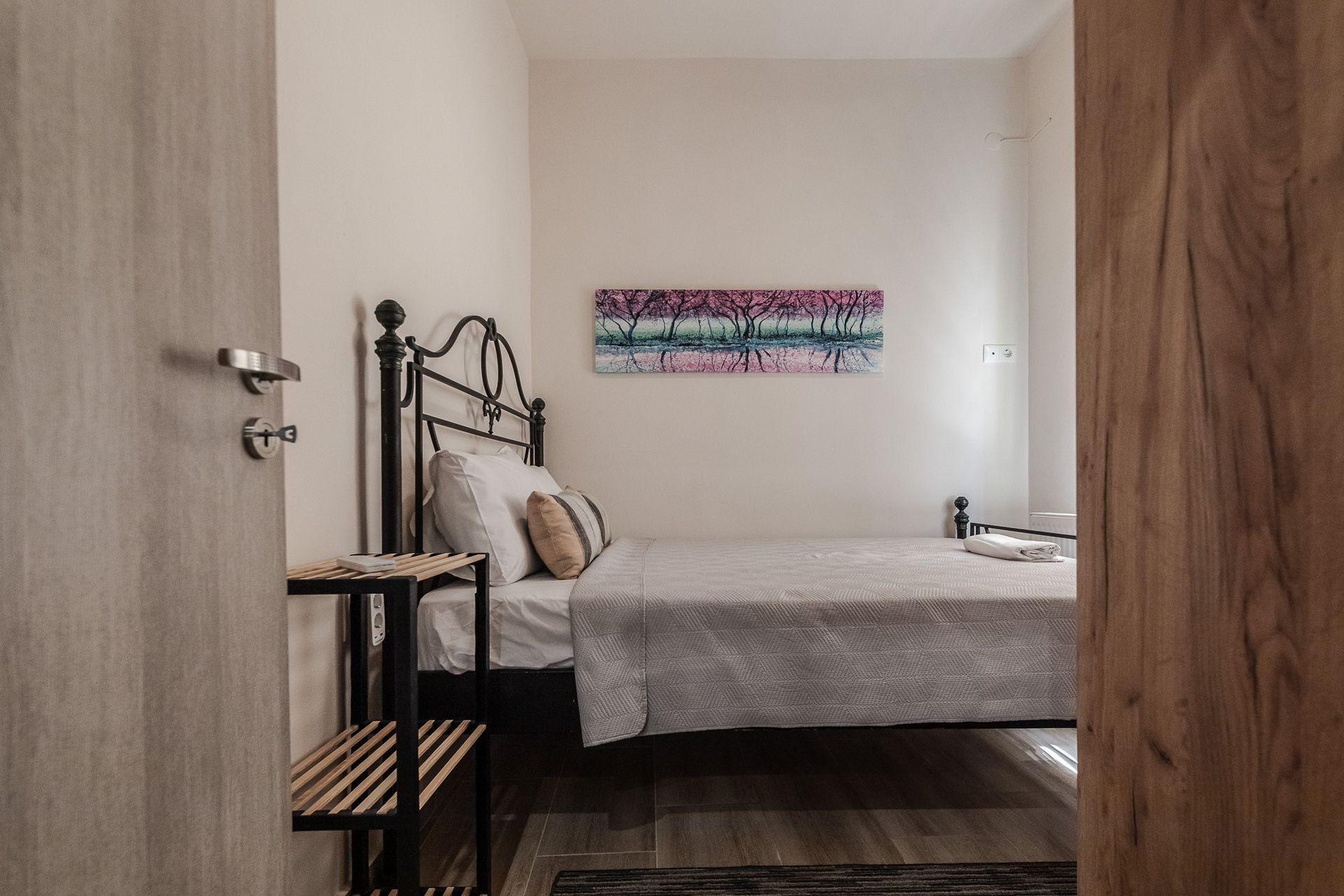 Small bedroom with a metal bed frame, patterned pillows, and a colorful wall hanging.