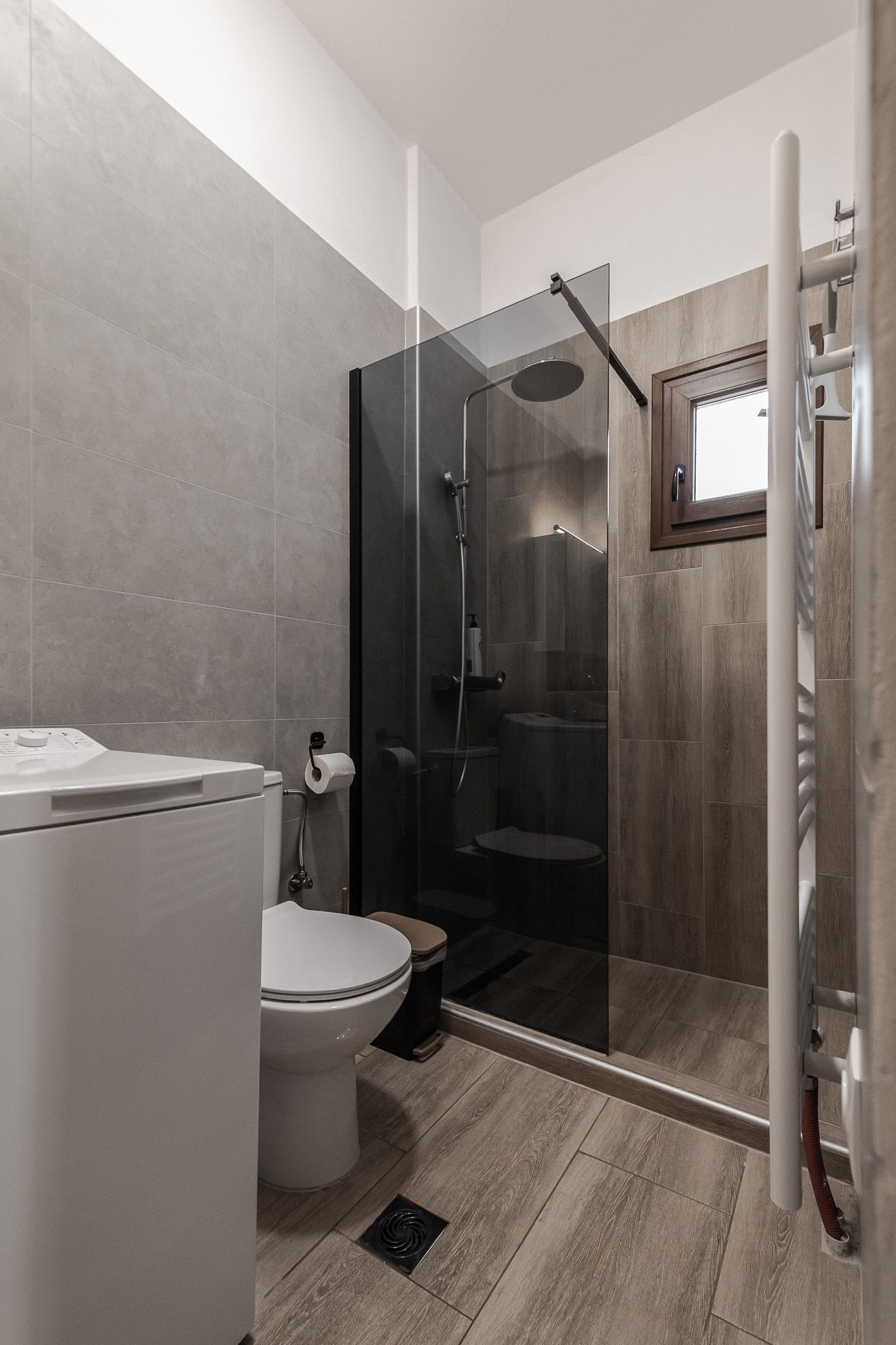 Small bathroom with a toilet, shower, sink, and wood-look tile flooring.