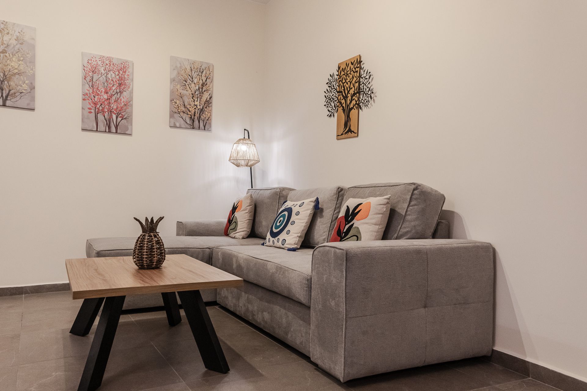 Modern living room with gray sofa, wooden coffee table, floor lamp, and abstract wall art.