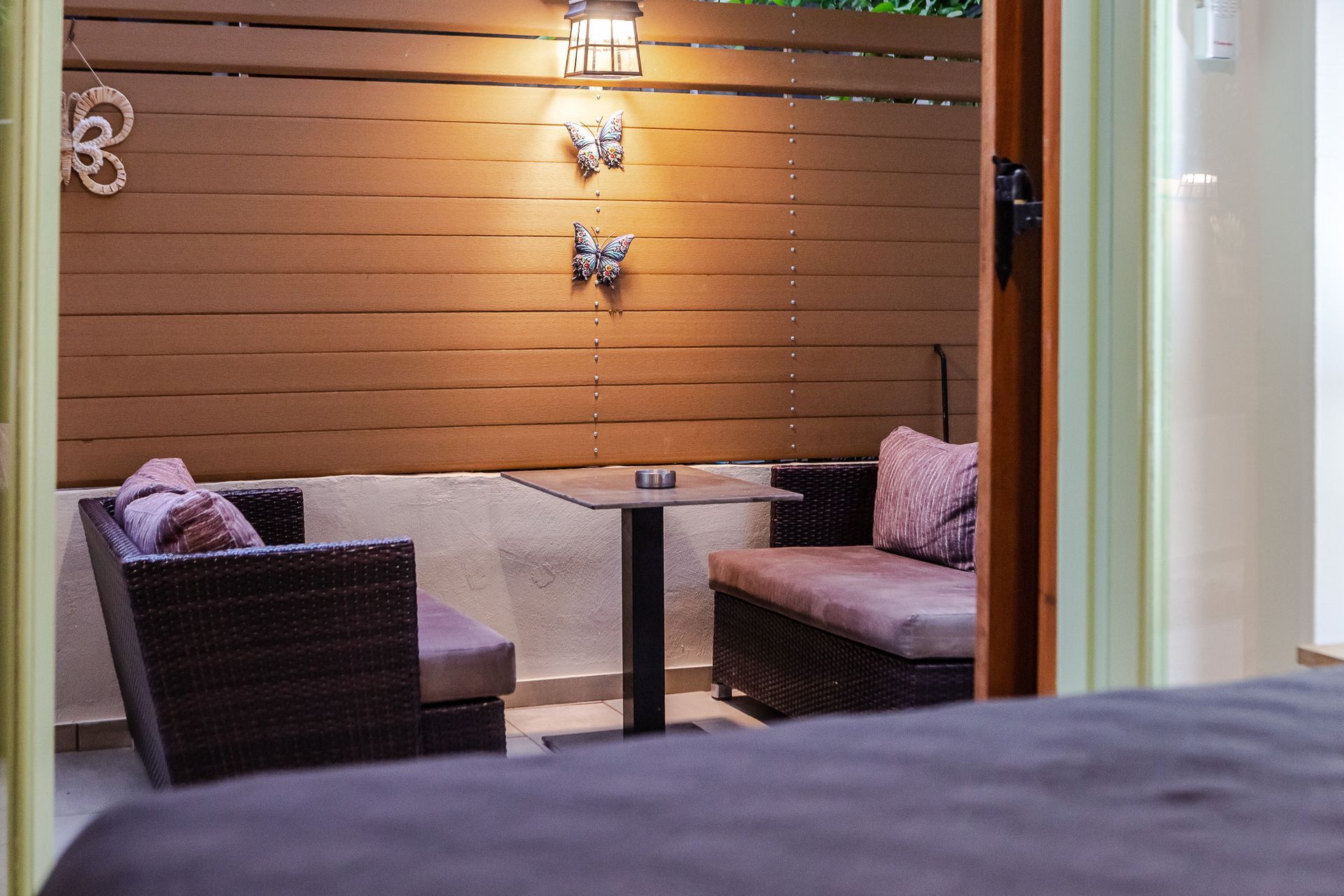 Cozy outdoor patio with wicker seating, wall lights, and a wooden slat backdrop