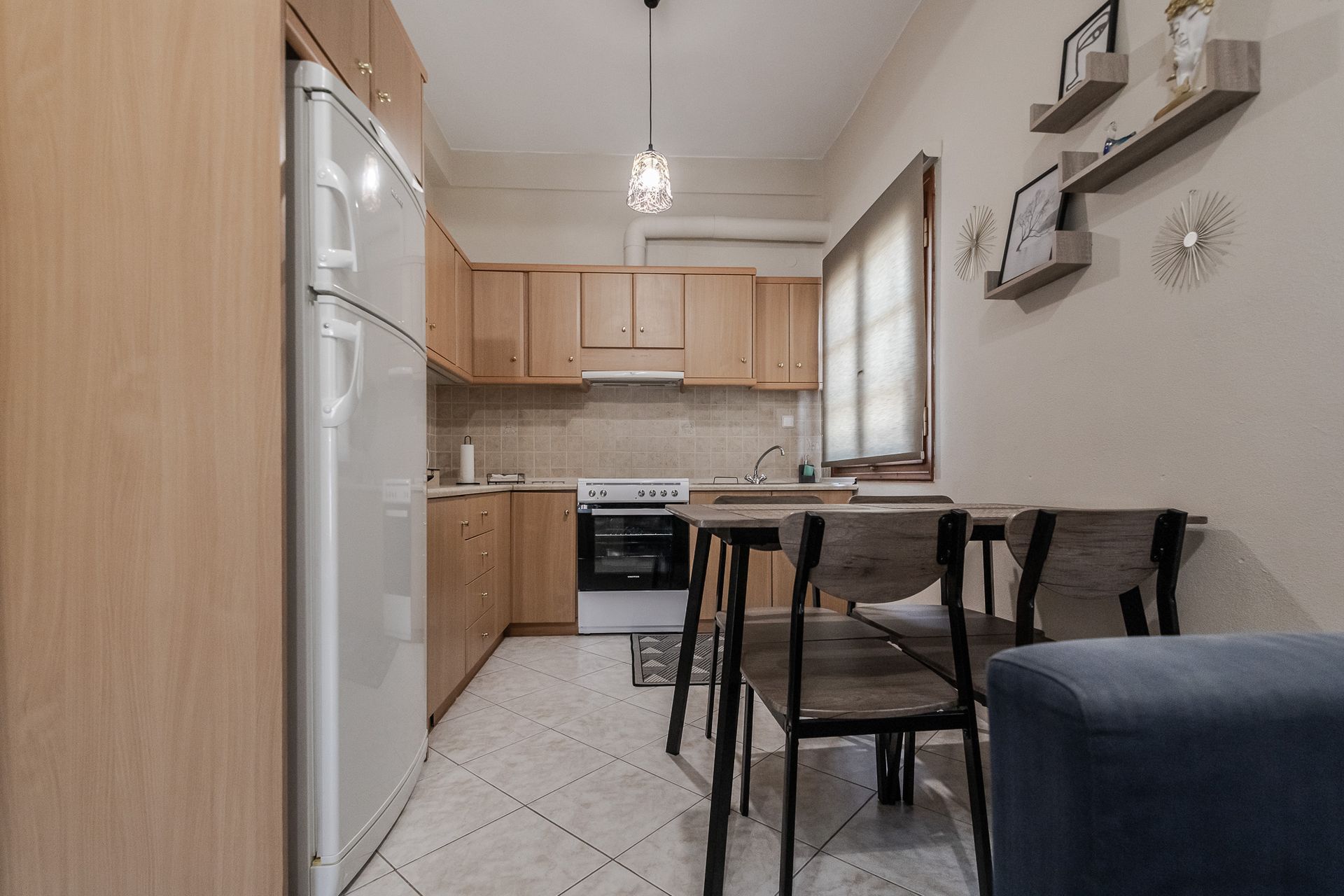 Compact kitchen and dining nook with light wood cabinets, white appliances, and a small table by the window.