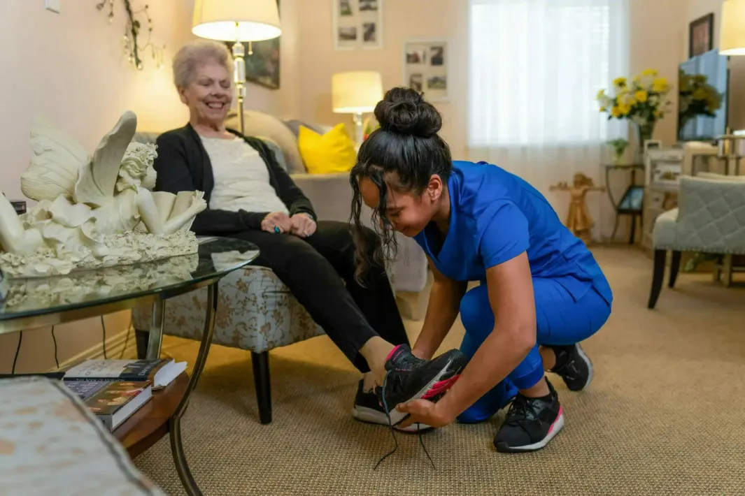 A nurse is helping an elderly woman walk on parallel bars.