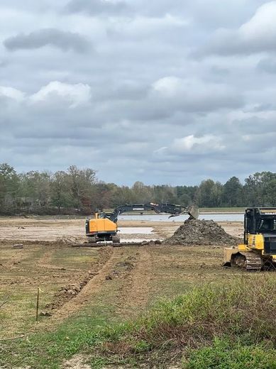 Construction site with excavators grading a dirt path under a cloudy sky
