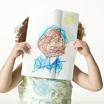 A little girl is holding a drawing in front of her face.