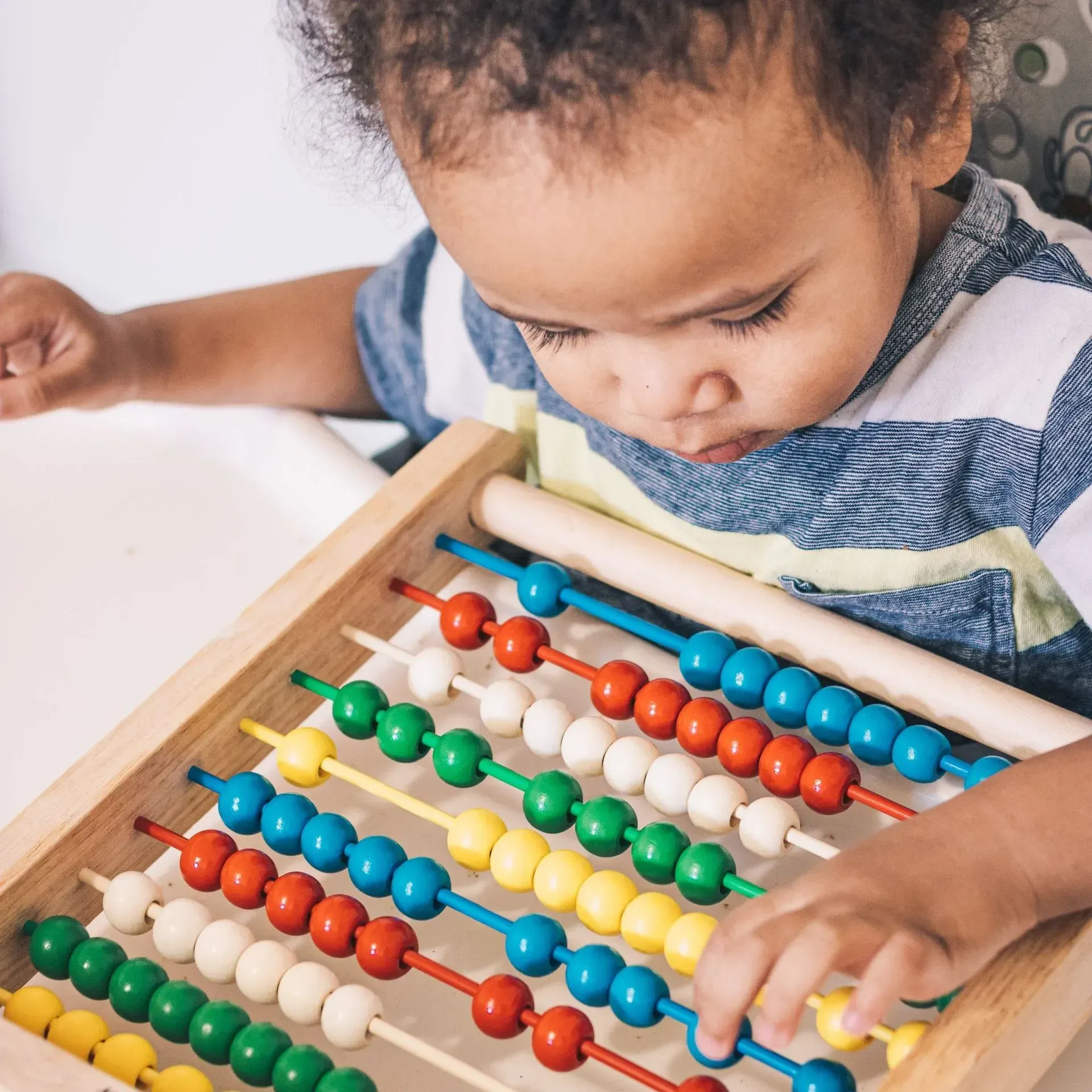 A child is playing with a colorful abacus