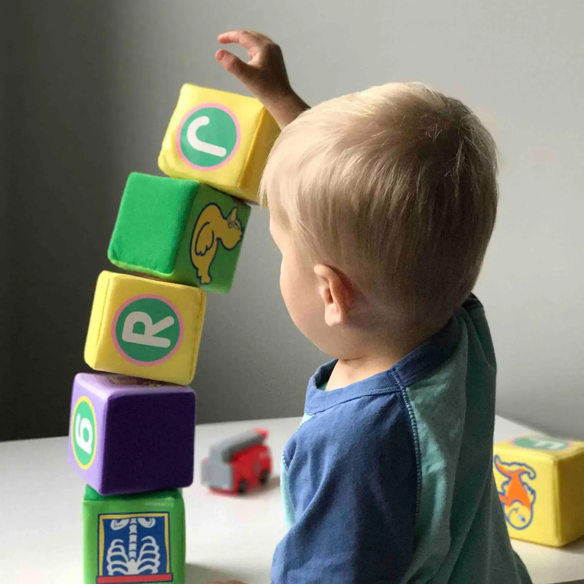 A young boy is stacking alphabet blocks on top of each other.