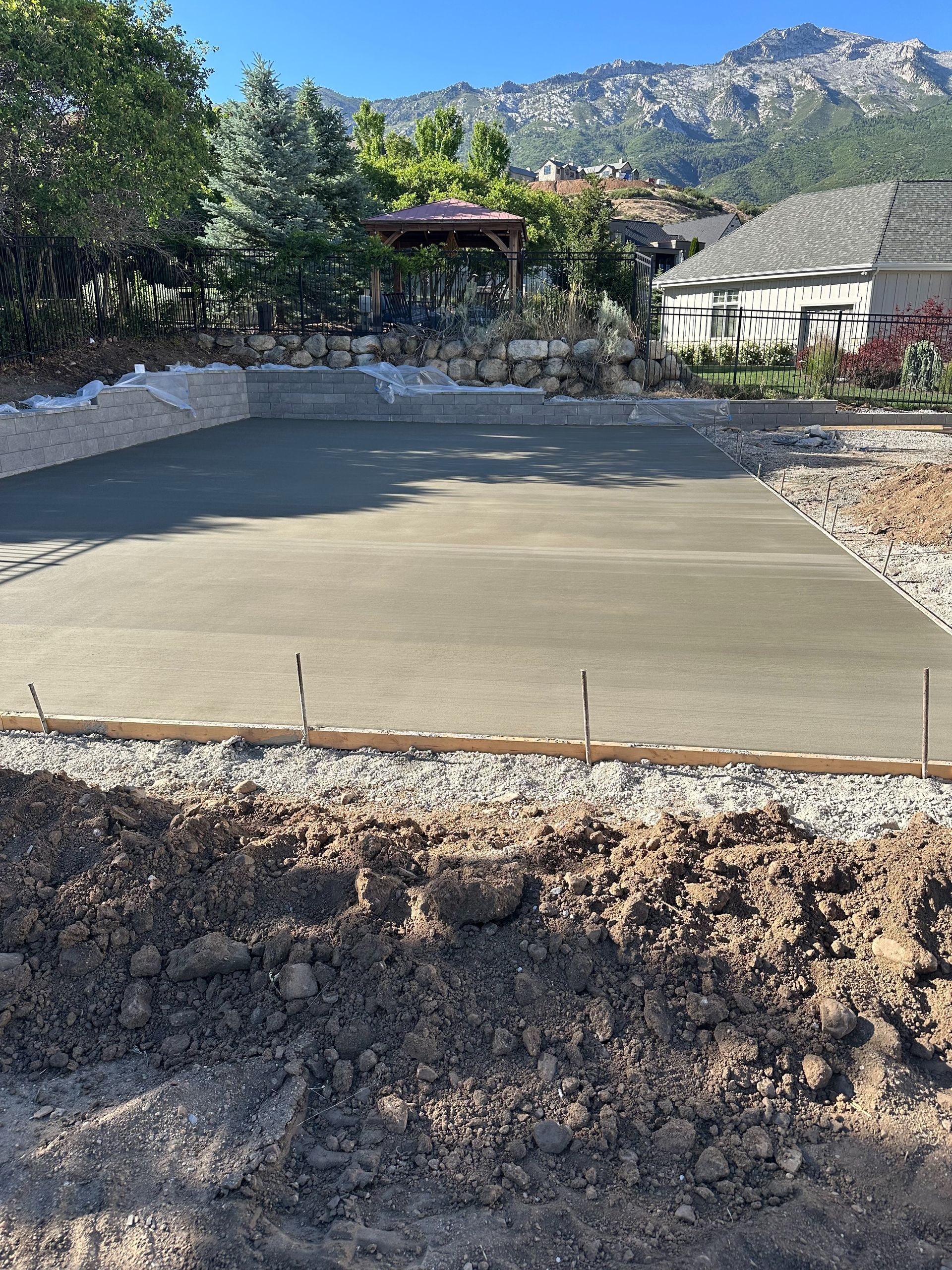 Fresh concrete foundation slab in a backyard with mountains and trees in the background
