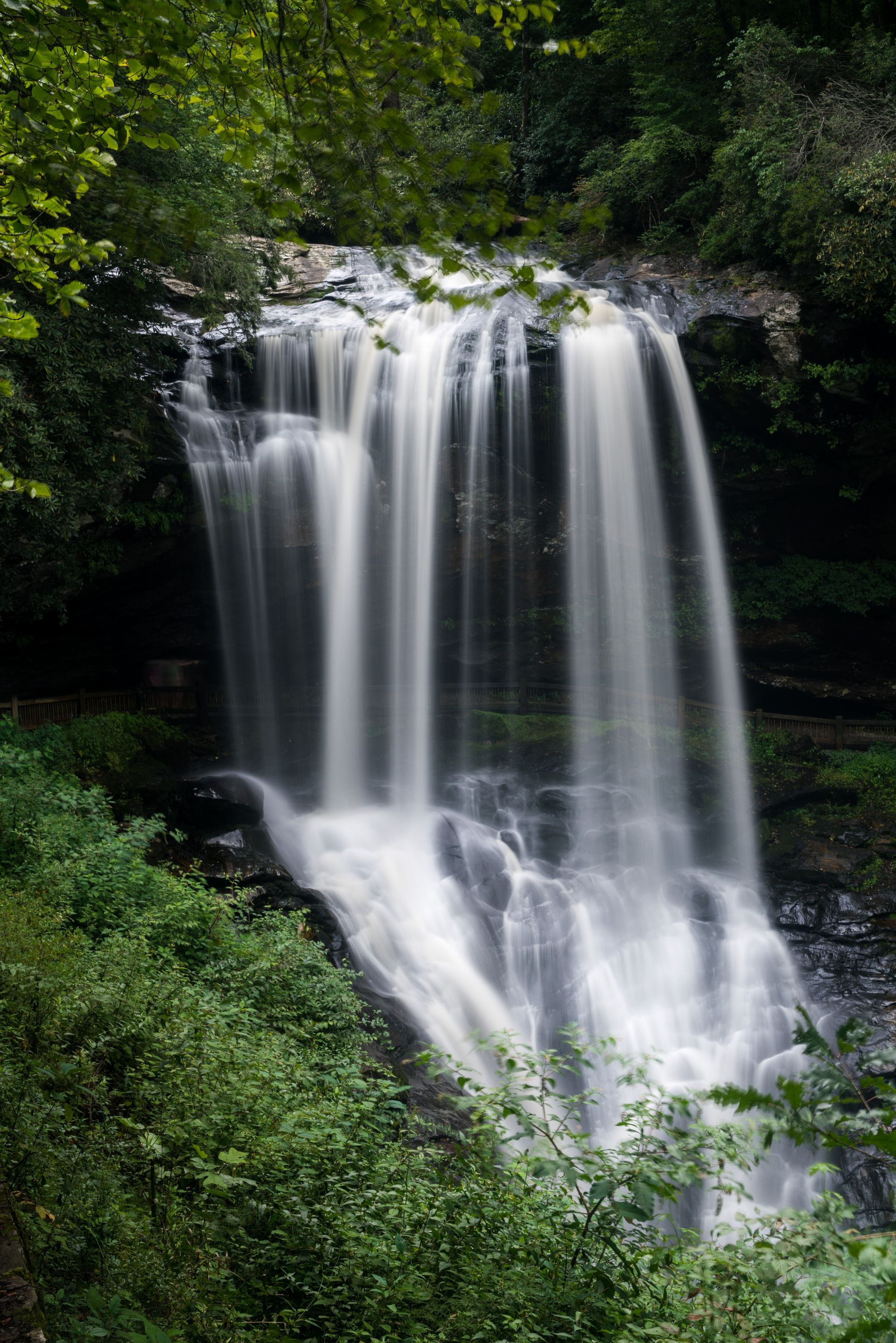 Waterfall cascading over rock formations, surrounded by lush green vegetation.