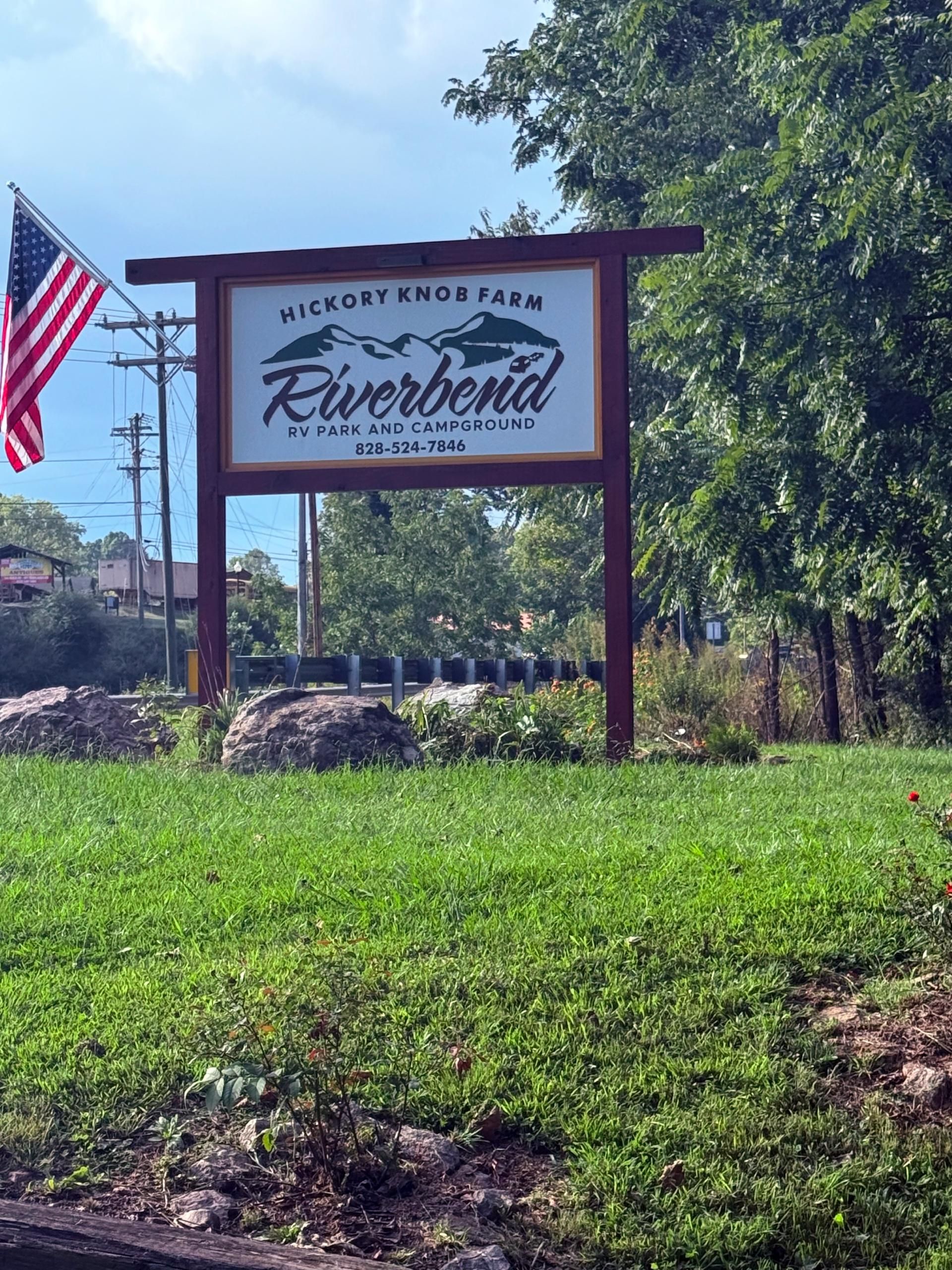Sign for Riverbend, a farm and inn, with American flag and trees.