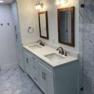 Bathroom with double sink vanity, two mirrors, and a tall cabinet. White cabinetry, marble floors.