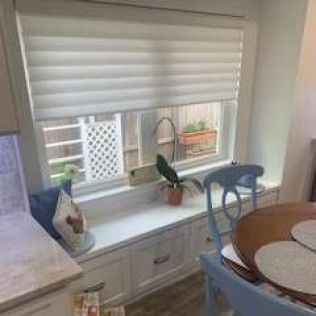 Window with blinds above a built-in bench. A plant sits on the sill.