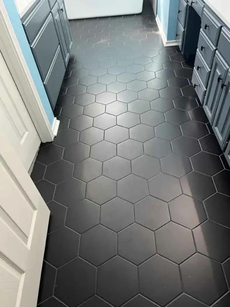 Dark gray hexagonal tile floor in a kitchen or bathroom, seen from above.