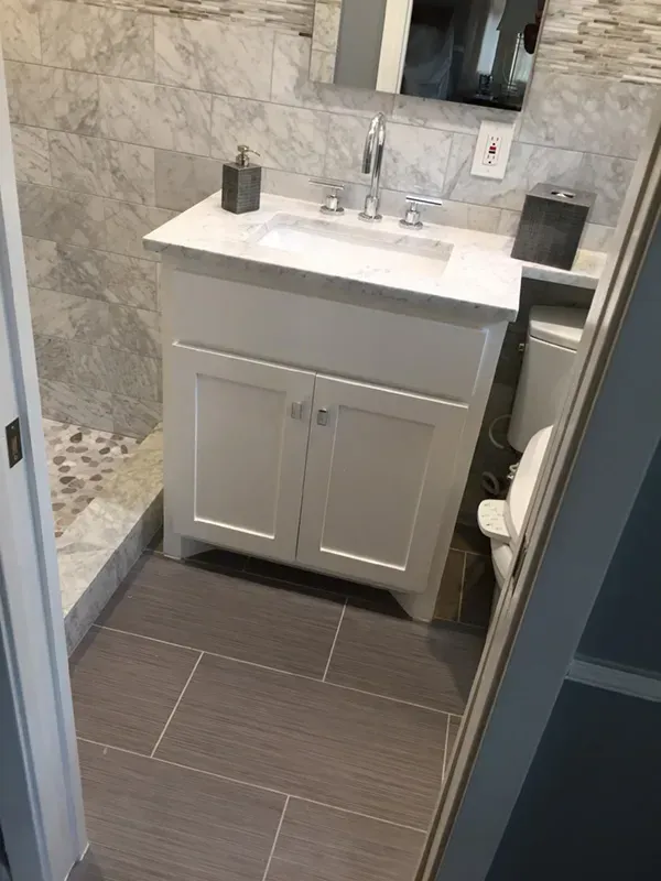 Small white bathroom with marble tile and white vanity.