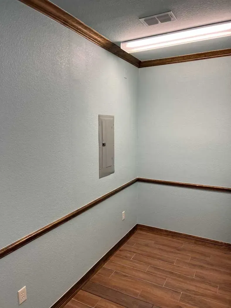 Small room with a light blue wall, wood floor, and electric panel.