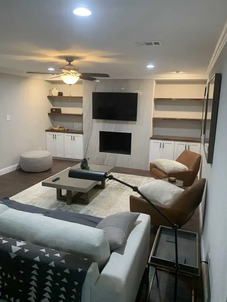 Living room with built-in shelves, a fireplace, and a TV. Features a couch, chairs, and area rug.