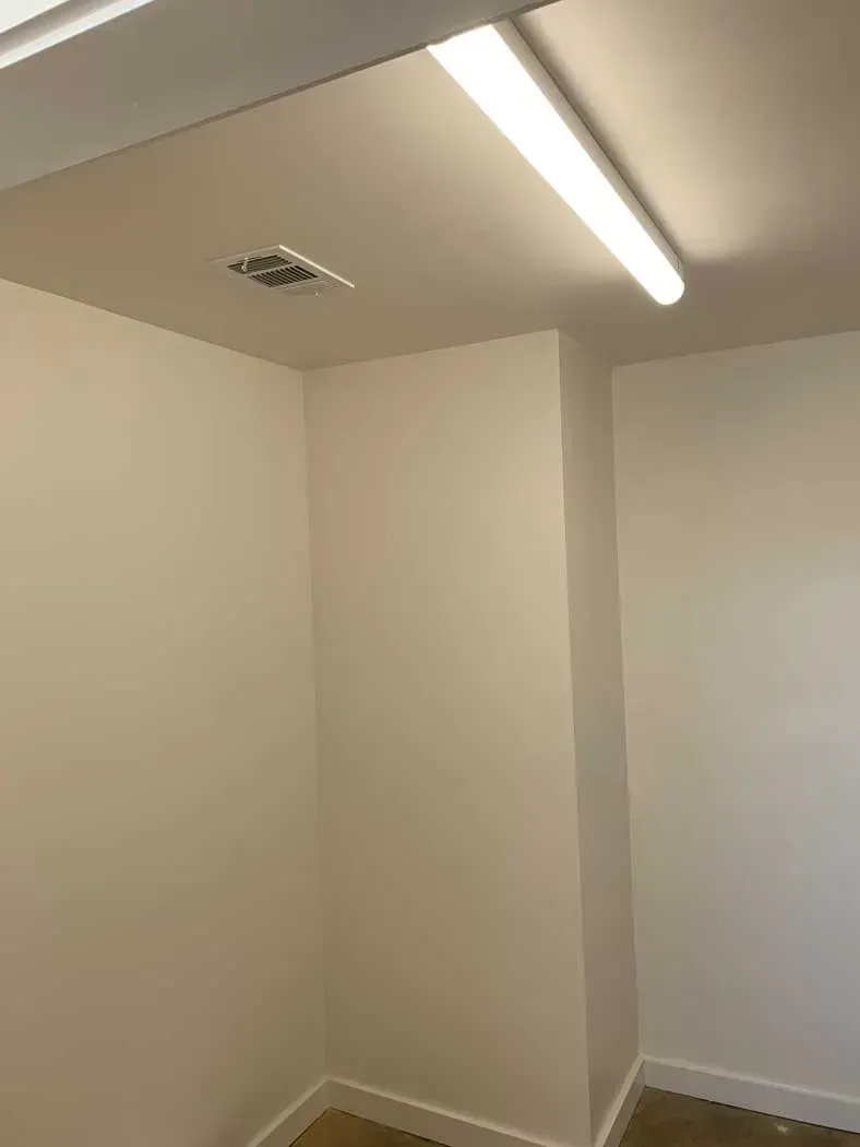 White walls and ceiling in a corner with a fluorescent light fixture.