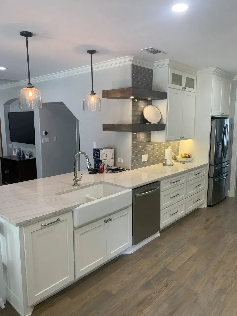 White kitchen with island, stainless steel appliances, and wooden shelves.