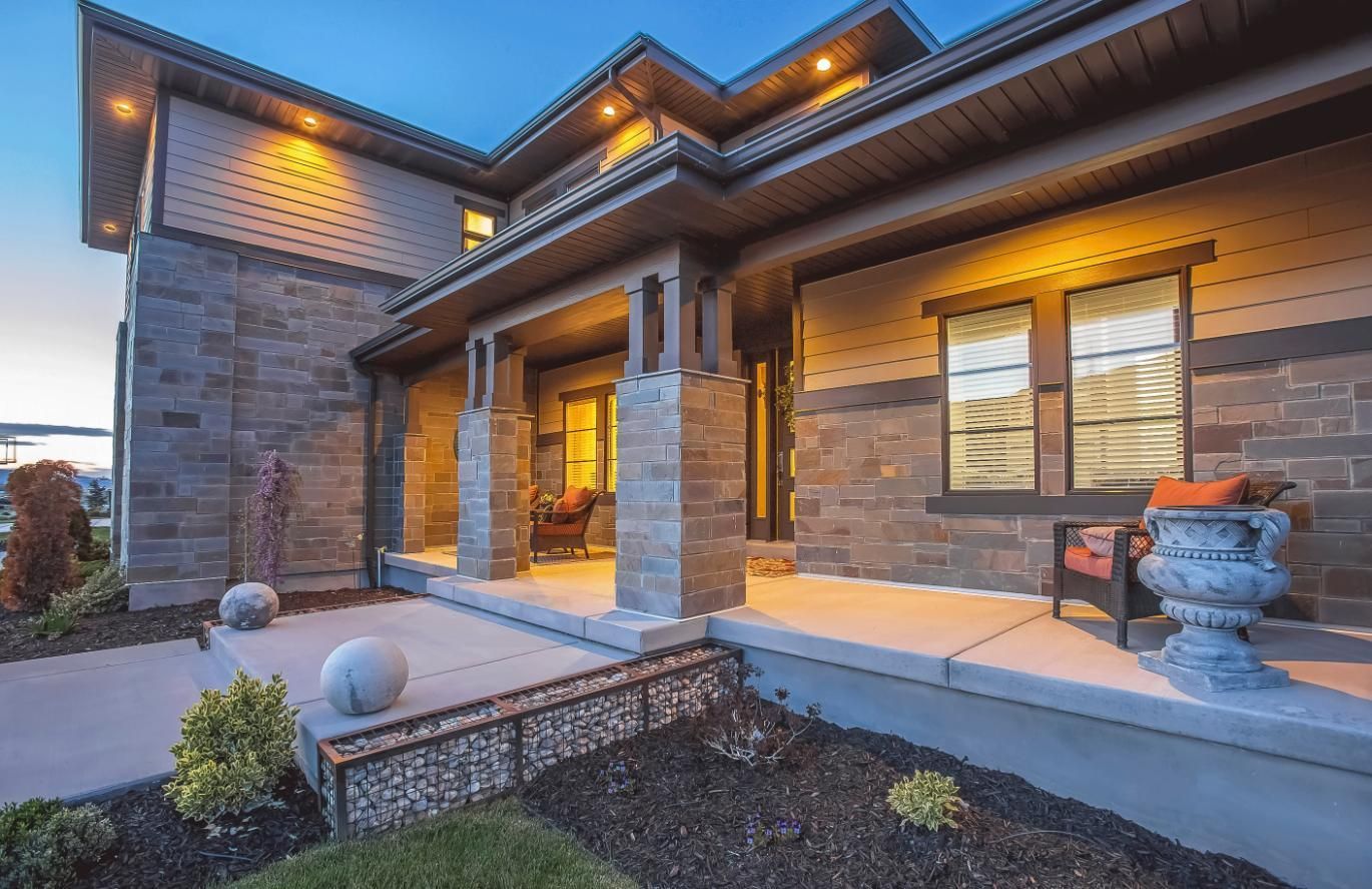 A modern home exterior with a stone facade, porch, and decorative urn.
