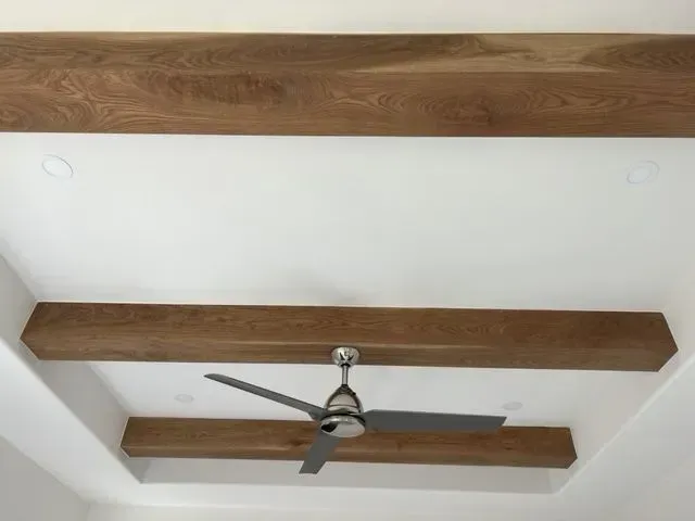White ceiling with wood beams, a ceiling fan, and recessed lighting.