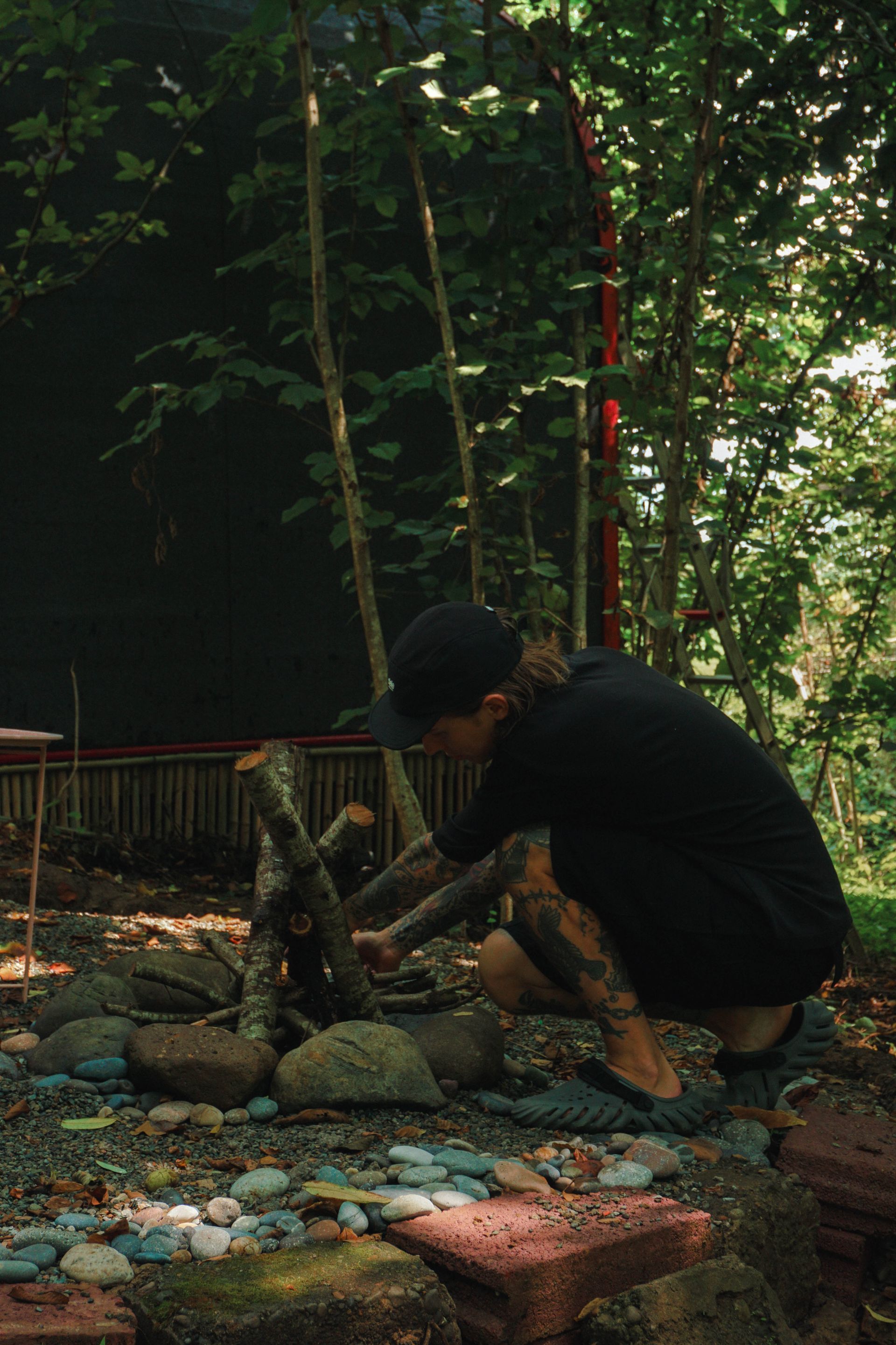 Preparing campfire at forest cabin fire pit, off-grid experience at Shromantic Garden Guria