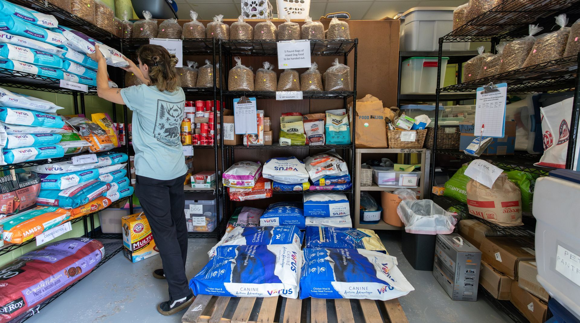 A volunteer adds pet food to the shelves of the SPCA's pet food pantry