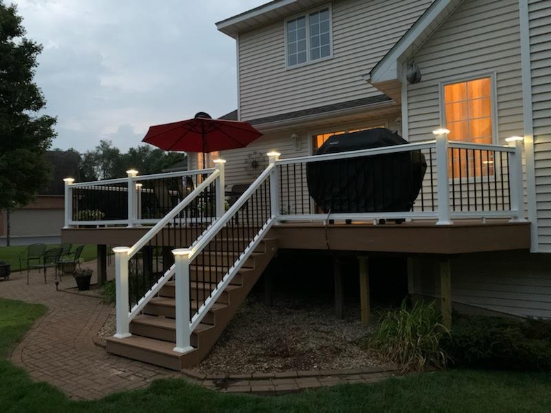 A deck with stairs and a red umbrella in front of a house
