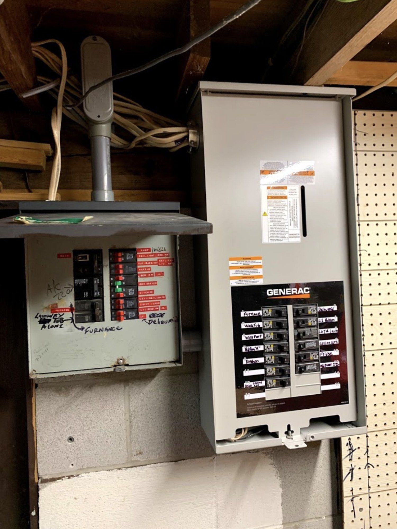 Two electrical panels are hanging on a wall in a garage.