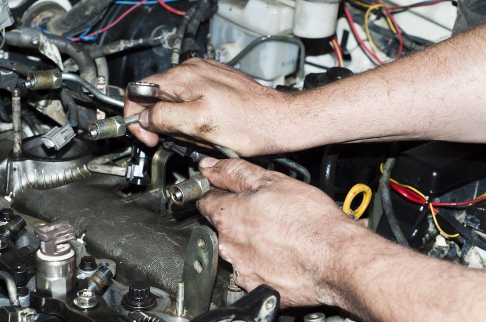 A Man Is Working On A Car Engine With A Wrench — Advanced Automotive Services In Smithfield, QLD