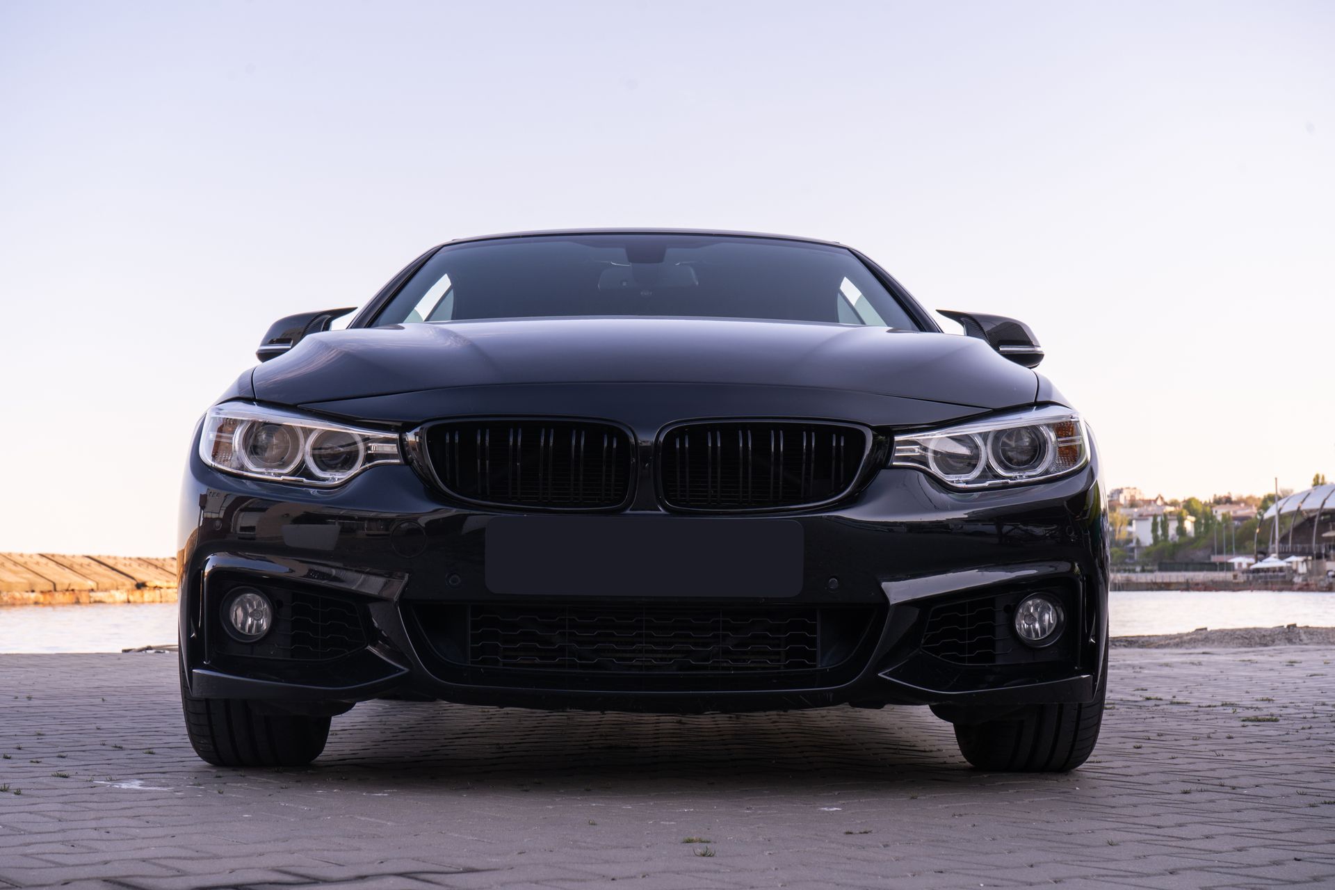 Front view of a black sports sedan parked on a road at sunset.
