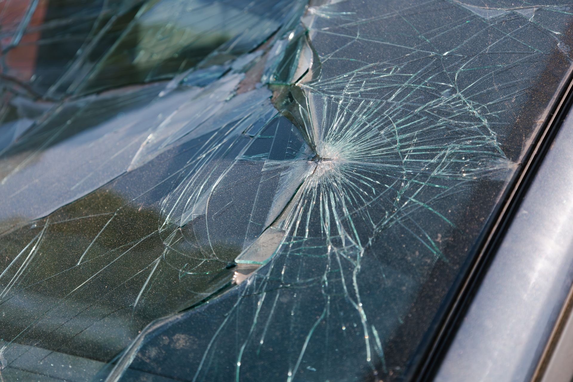 Cracked car windshield with shattered glass spiderwebbing across the right side