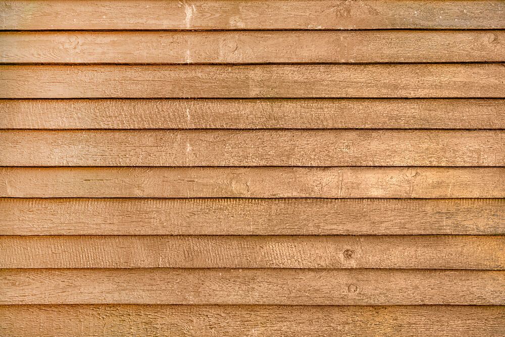 Horizontal wooden planks, weathered brown with visible grain, form a textured surface.