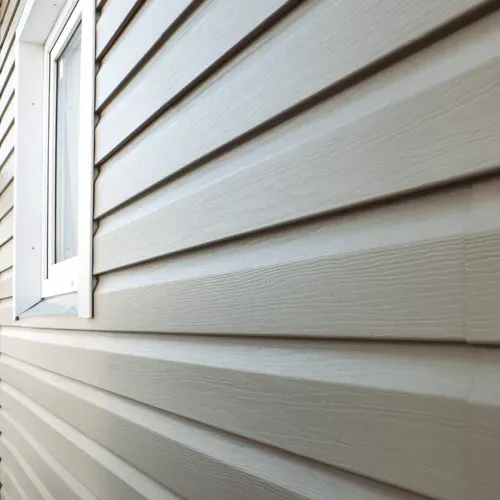 Beige siding on a house next to a white framed window.