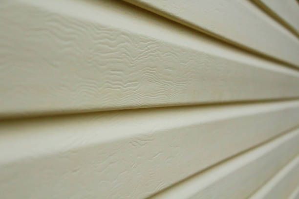 Close-up of light beige horizontal siding with a wood grain texture.