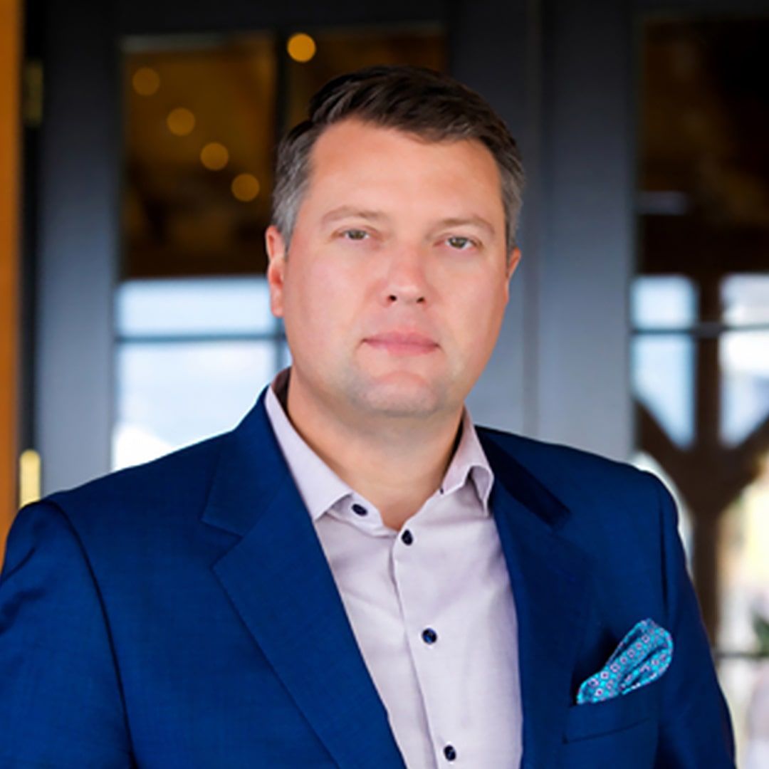 A man in a blue suit and white shirt is standing in front of a door.